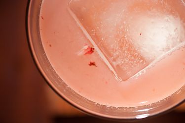 Overhead closeup of a Monkey See Monkey Do cocktail, served with a large ice cube.