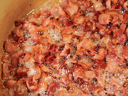 Small pieces of bacon crisping in a Dutch oven.