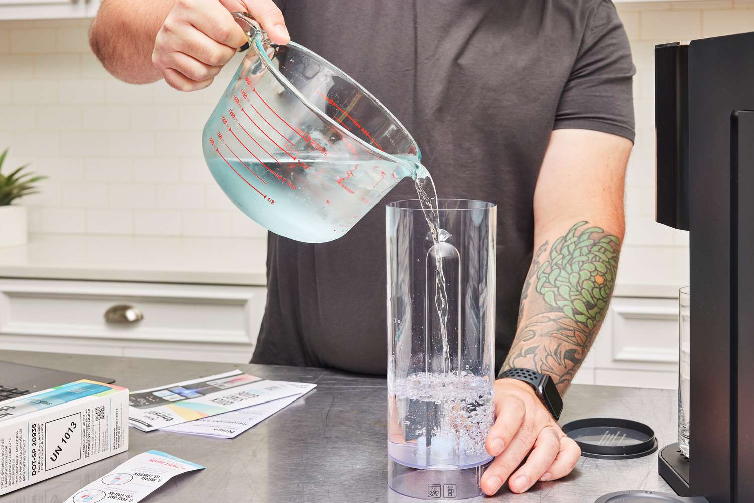 A hand pouring water into the water compartment of the Ninja Thirsti Drink System