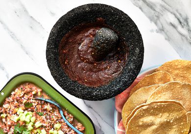 Overhead view of salsa negra in a molcajete with tostadas and ceviche
