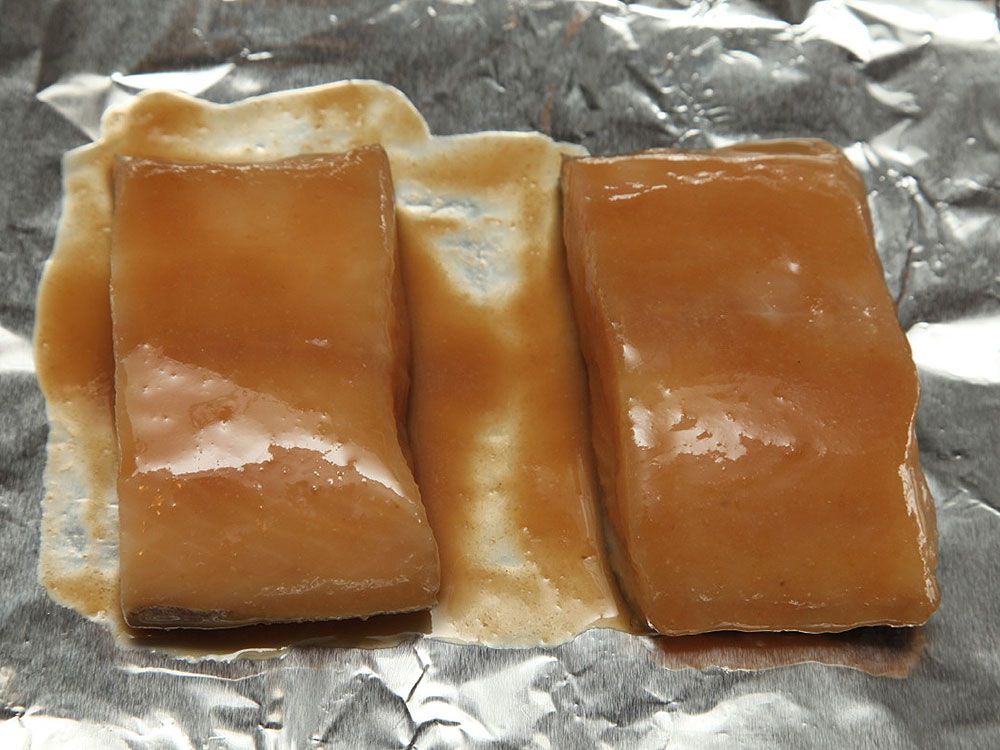Marinated pieces of black cod fillet are placed on a foil-lined baking sheet.