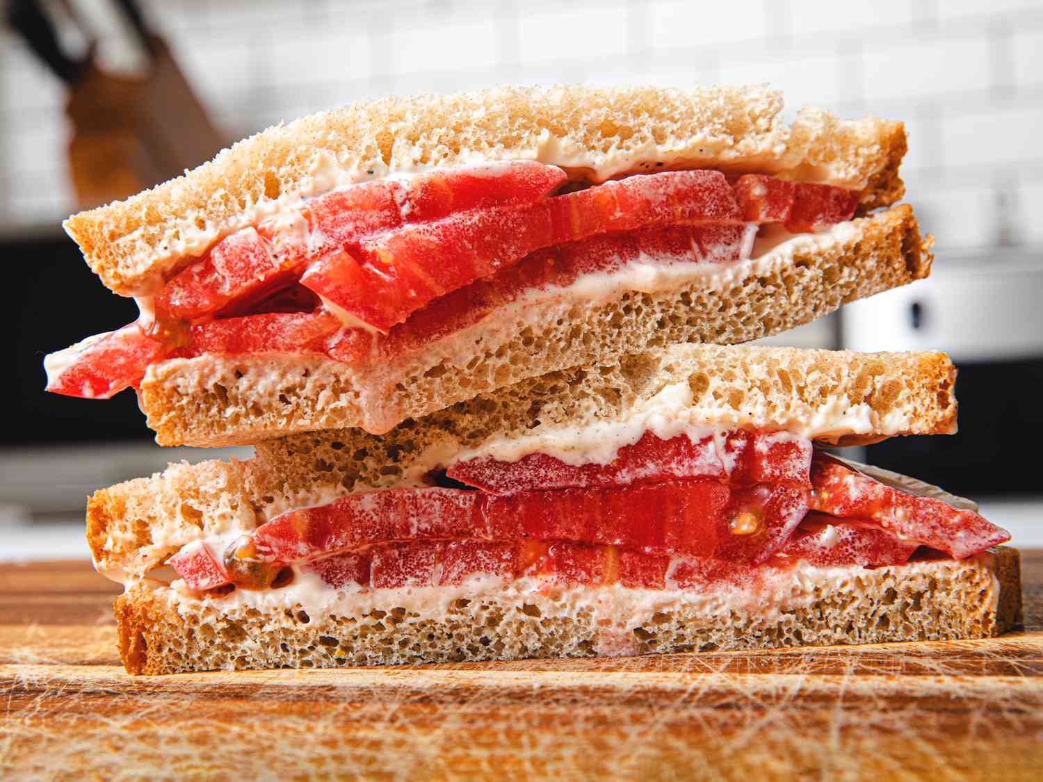 Classic tomato sandwich on a cutting board, cut diagonally and stacked.