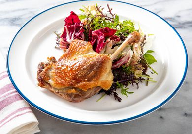 A plate of crispy duck and bitter greens.