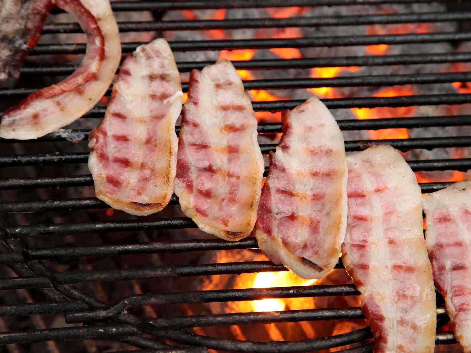 bacon on a charcoal grill over bright embers