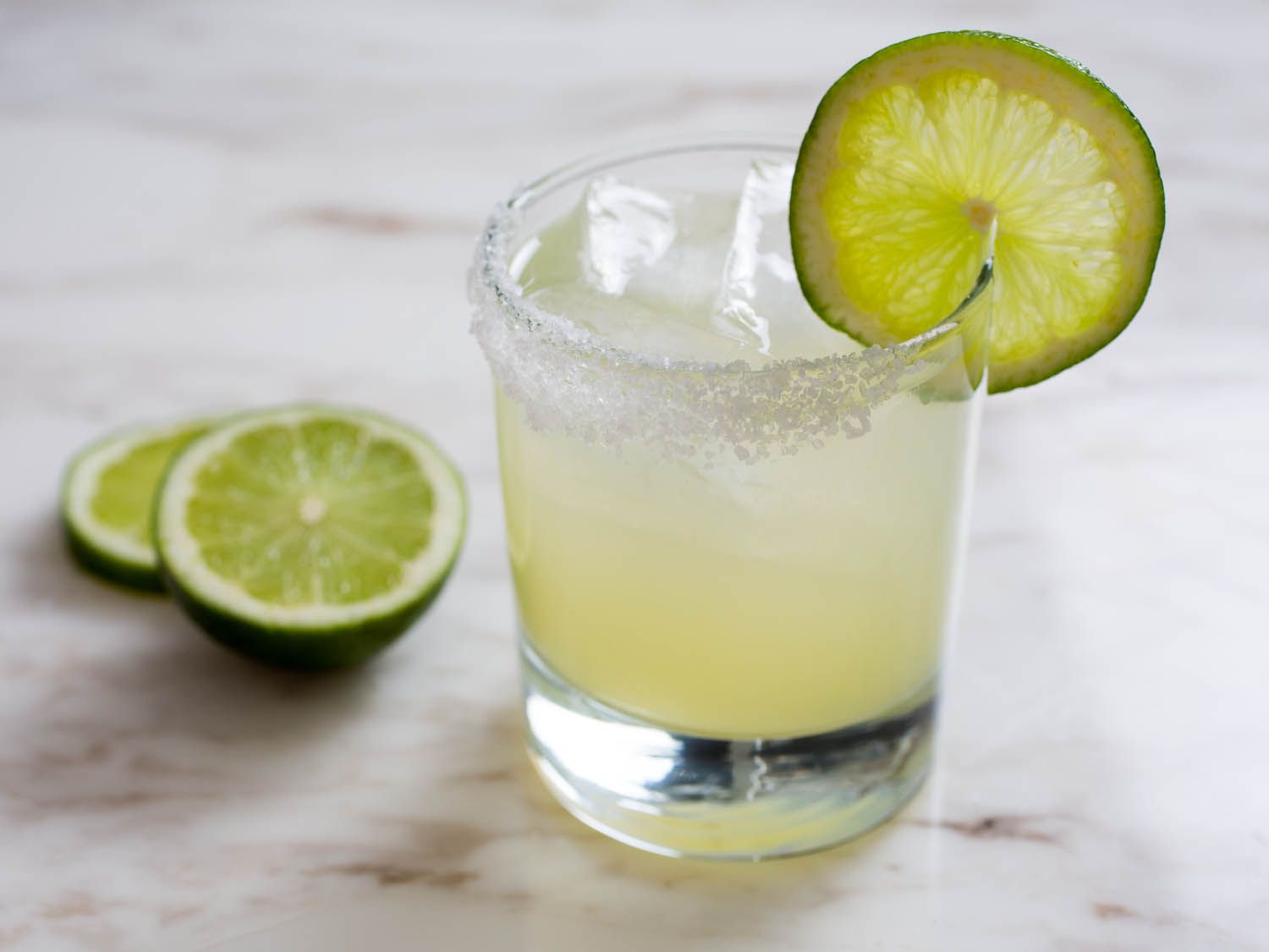A classic margarita in rocks glass with lime wheel on salted rim 