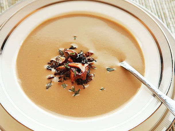A finished bowl of creamy chanterelle soup, topped with the sautéed mushrooms and a scattering of thyme leaves.