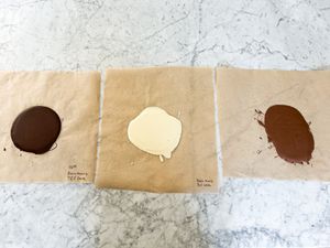 Three samples of melted chocolate on paper labeled with their respective descriptions