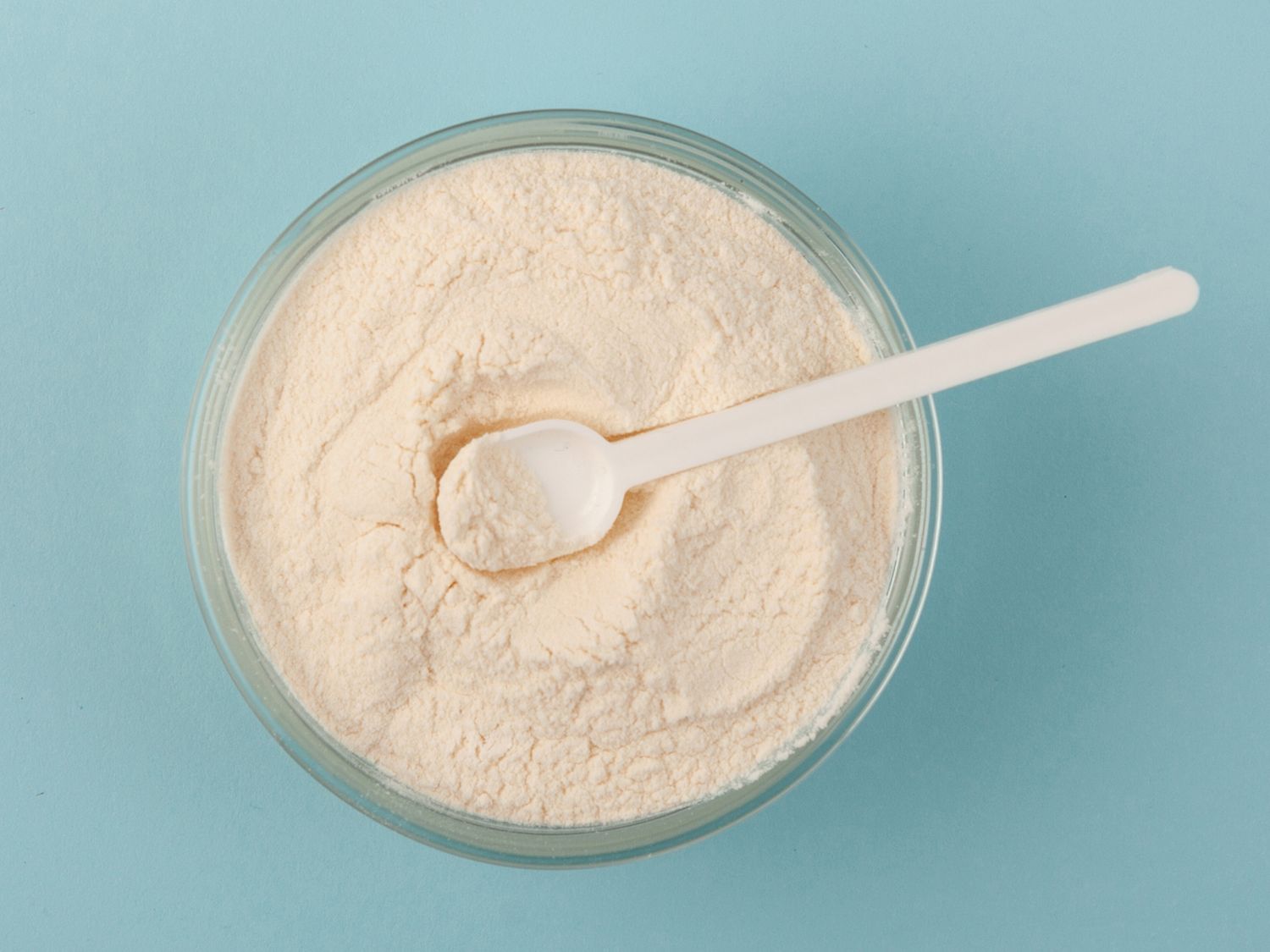 A bowl of powdered supplement or food product with a white scoop on top