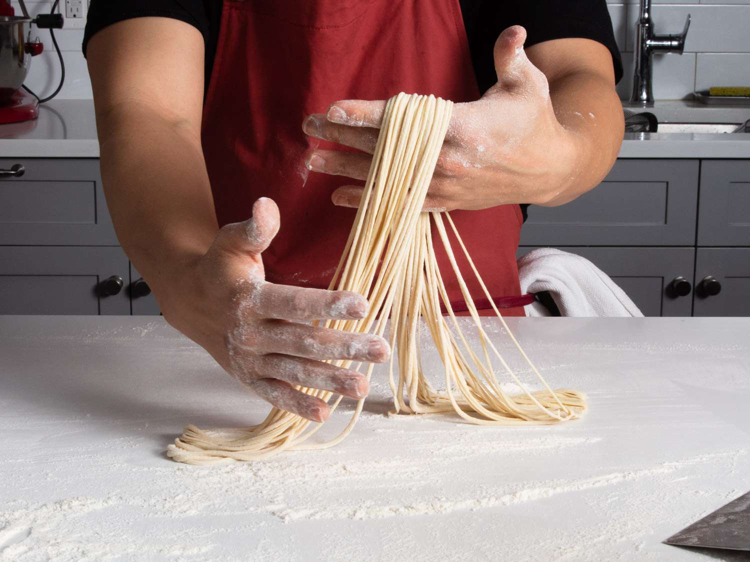 Hands holding thin hand-pulled noodles.
