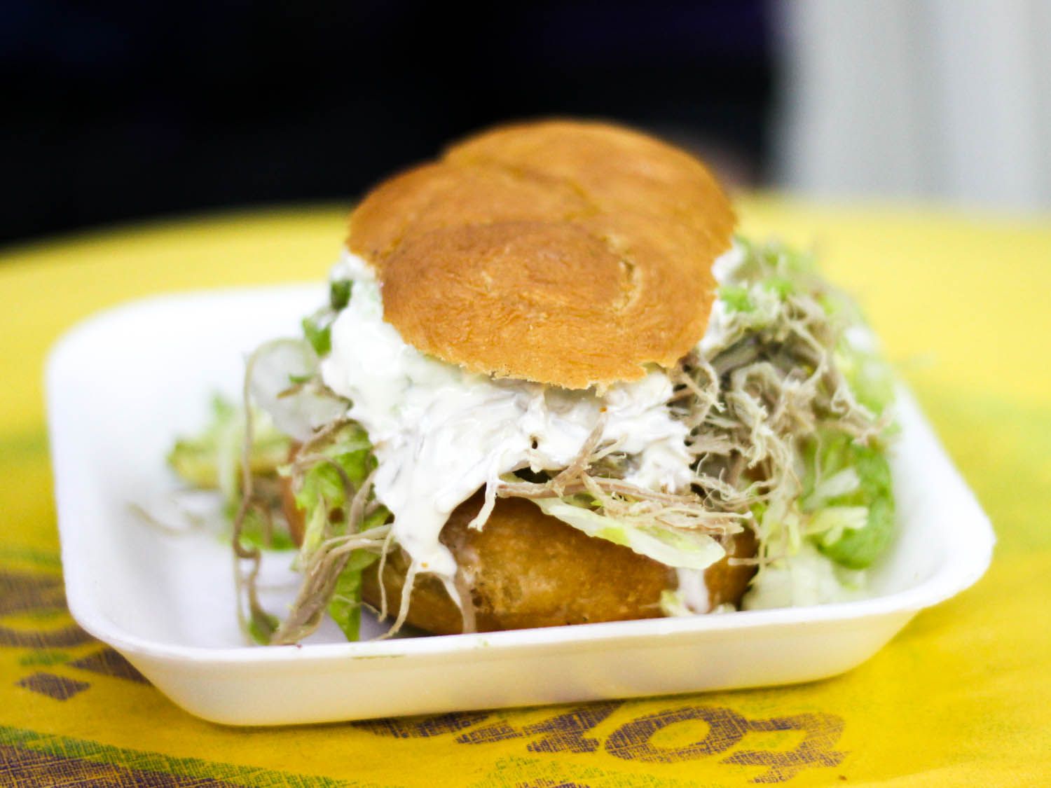 pelona sandwich stuffed with shredded beef, lettuce, chopped avocado, and crema 