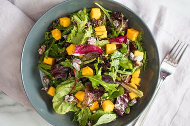 Overhead view of a colorful, mango-studded salad dressed with lemon poppy seed dressing.