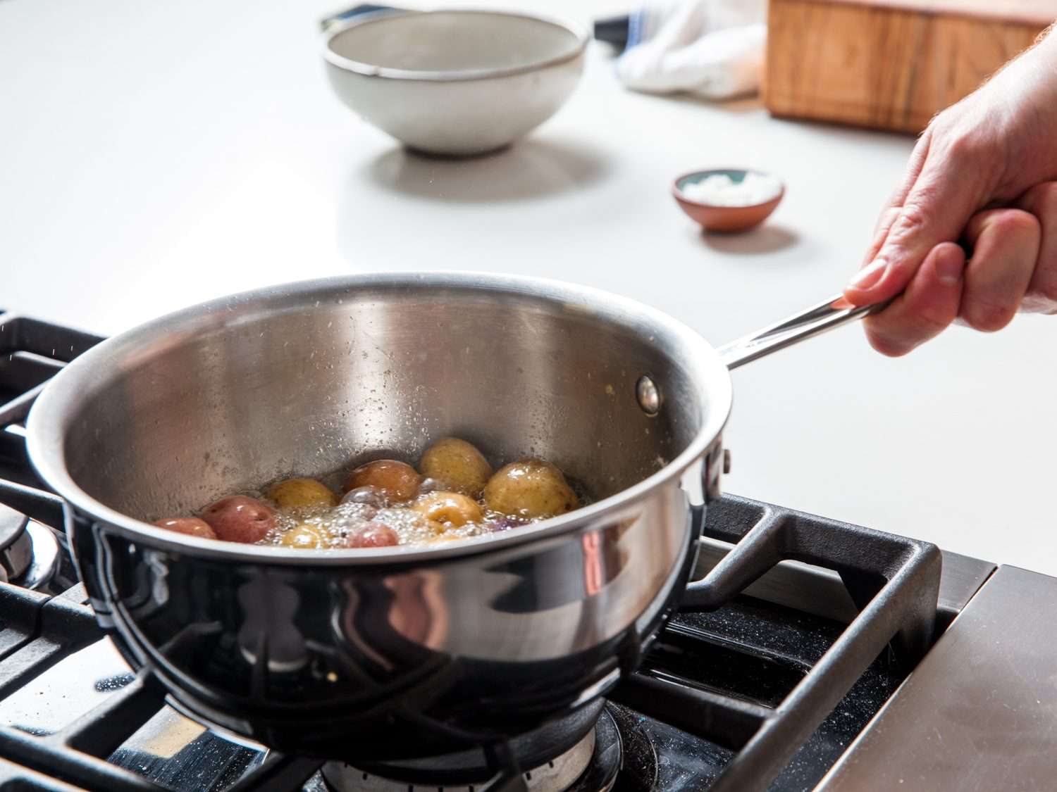 Swirling a saucepan with potatoes and butter.