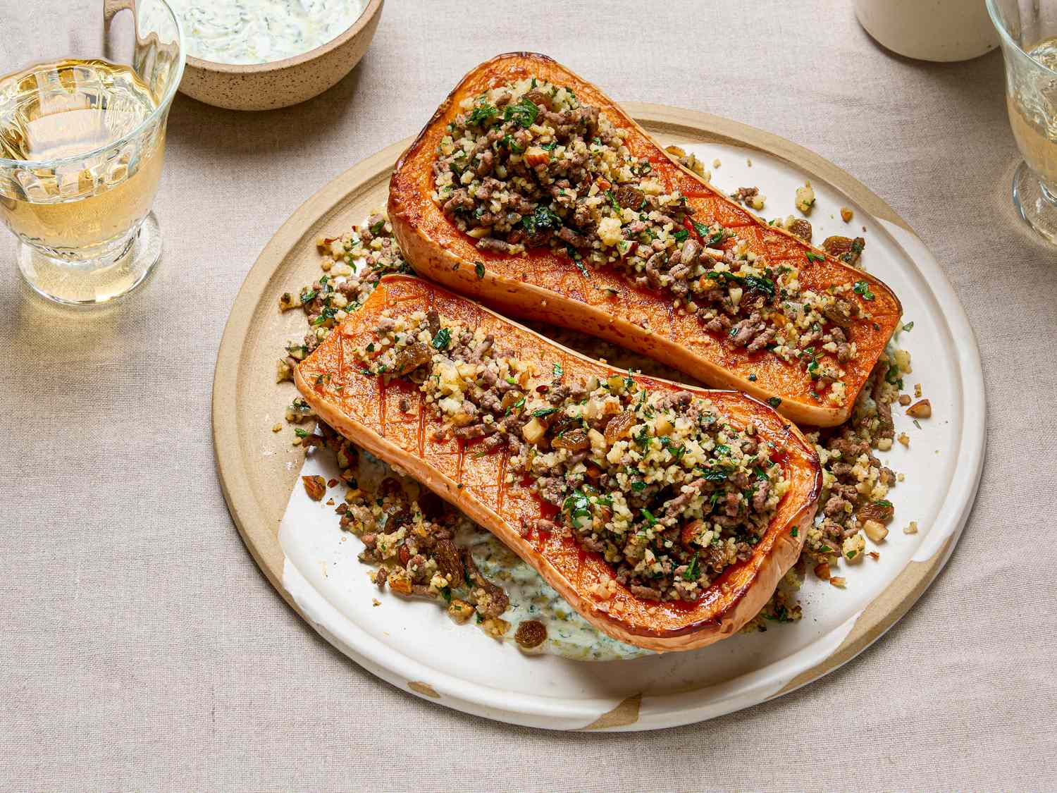 Butternut squash halves stuffed with a spiced couscous and mixed topping served on a white plate