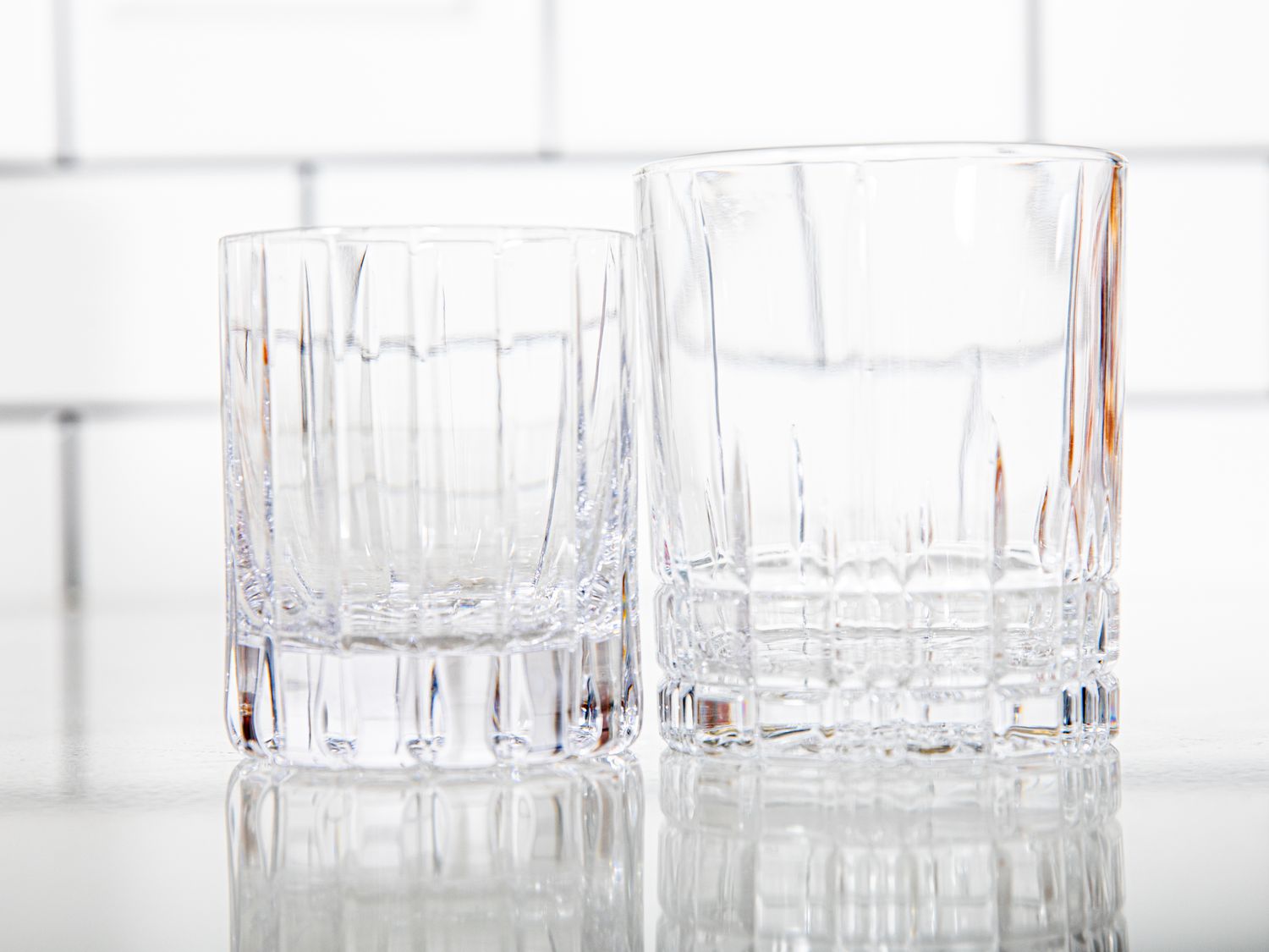 Two whiskey glasses on a kitchen countertop.