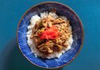 pork ginger over rice garnished with kizami shoga in a blue patterned bowl