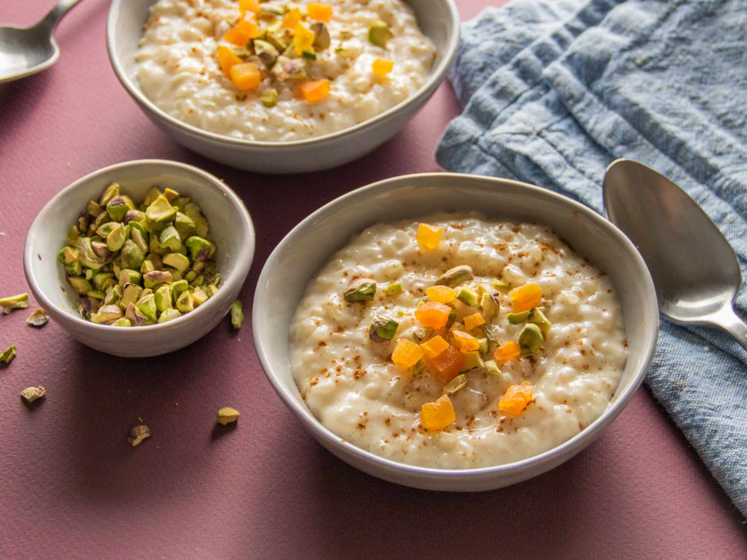side angle of rice pudding in bowls topped with dried apricot and pistachios