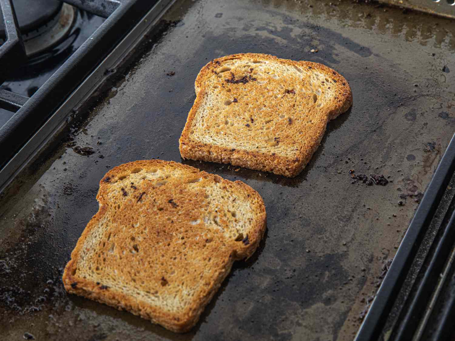 Bread being toasted on a girdle in bacon fat