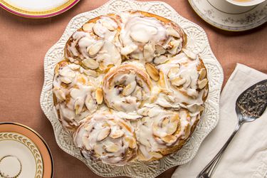 overhead of frangipane rolls on white platter, with 2 cups of tea on a pink tablecloth 
