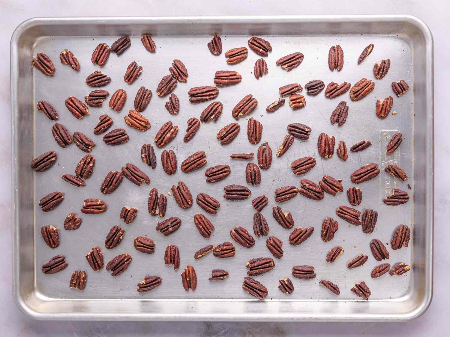 A baking sheet with evenly spread pecan halves