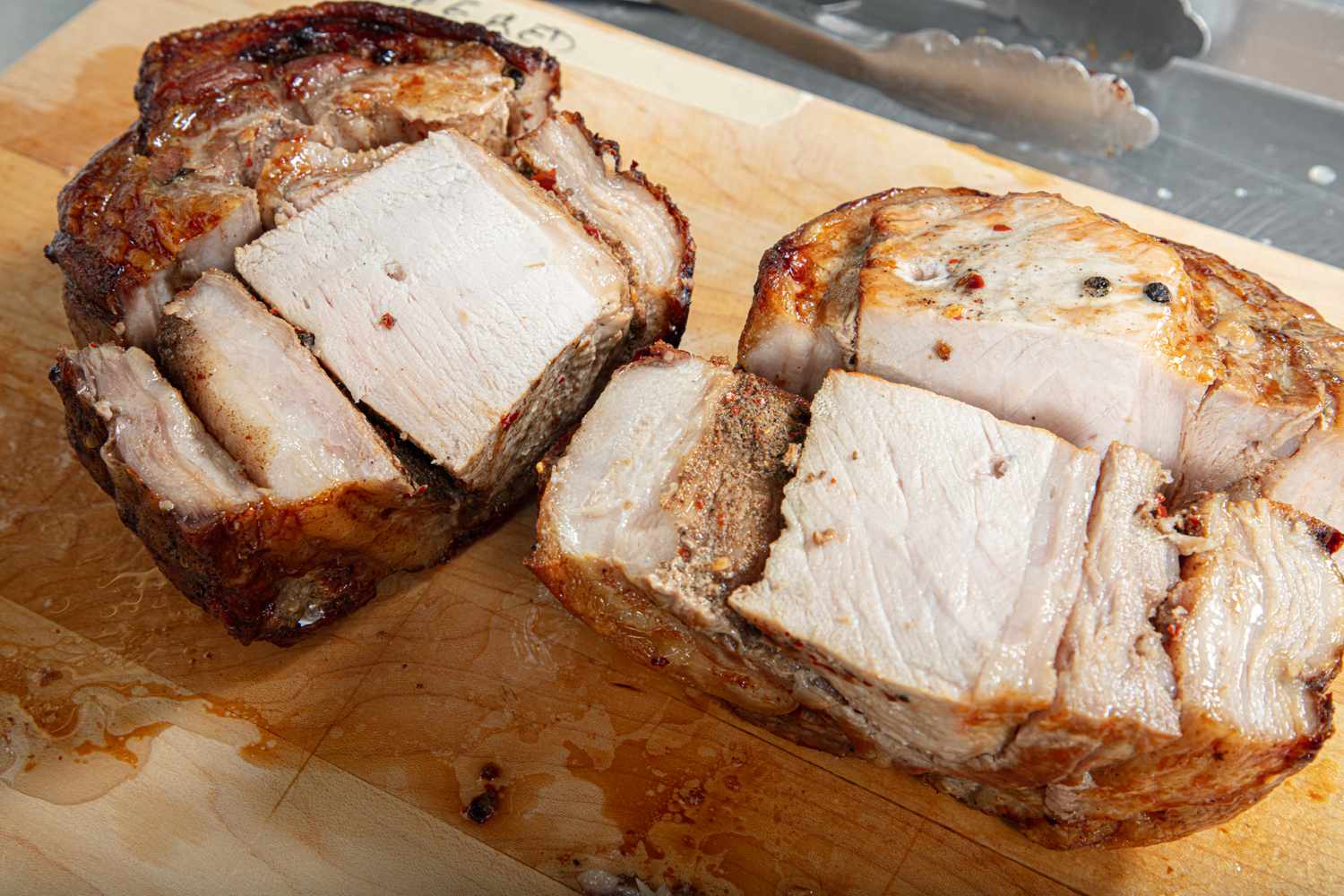 Two roasted meat cuts on a wooden cutting board partially sliced to reveal the texture