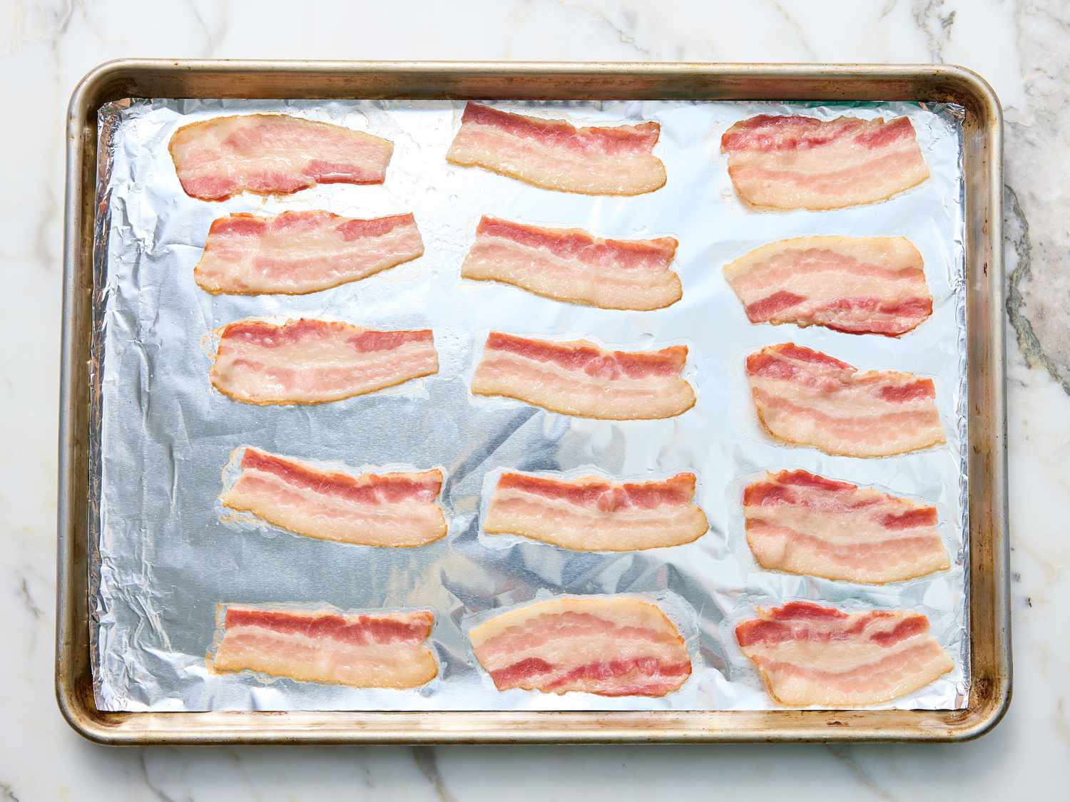 Slices of bacon arranged on a foillined baking tray