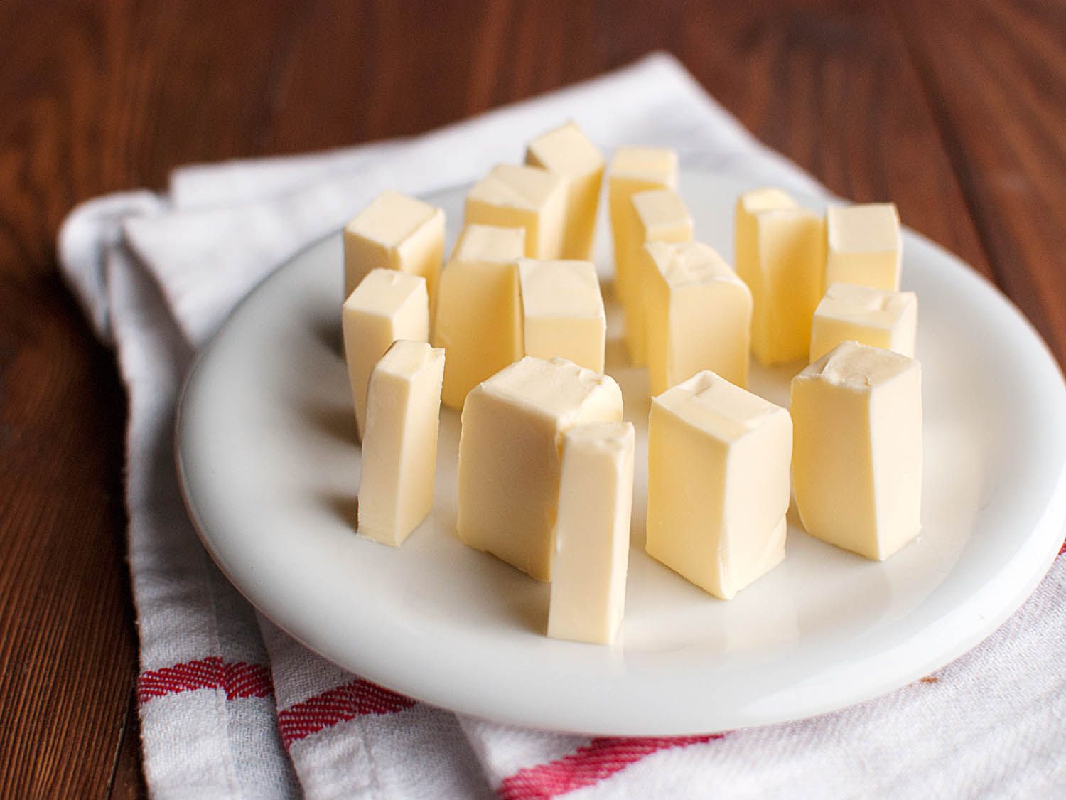 Many cubes of butter resting on a white plate.