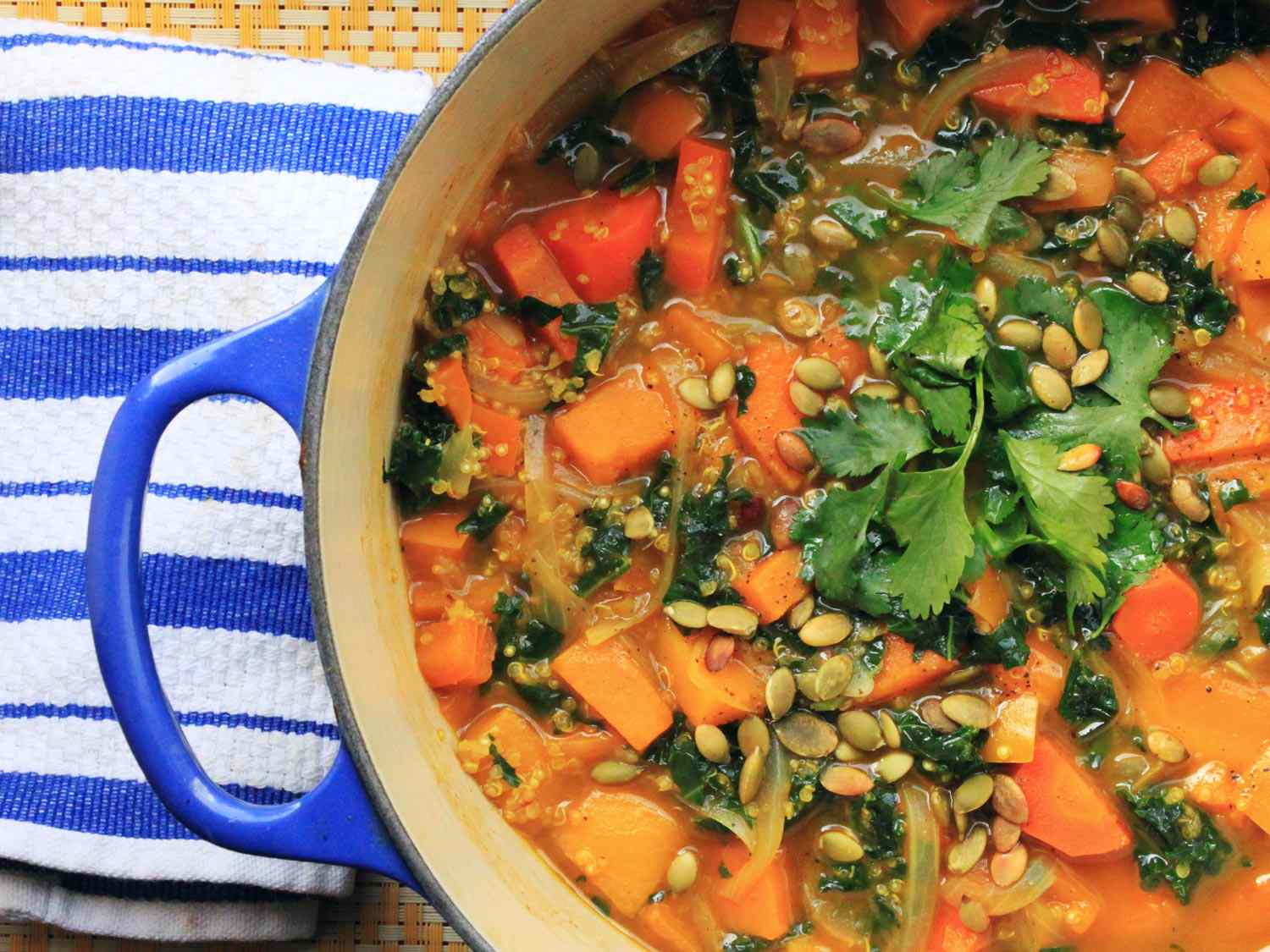 A blue Dutch oven filled with vegan butternut squash soup with kale.