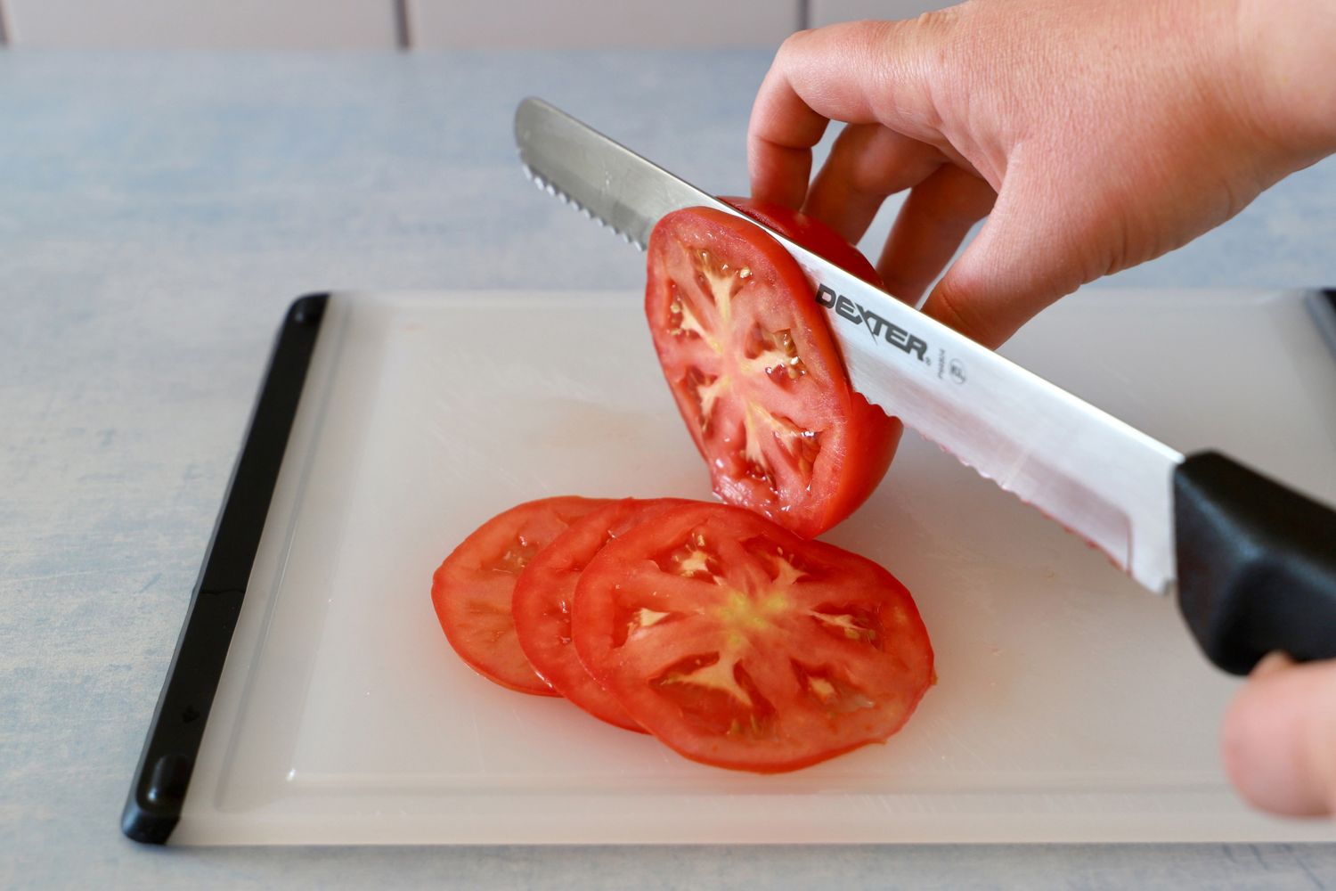 Person slicing tomato with Dexter-Russell Basics 10-Inch Bread Knife With Black Polypropylene Handle