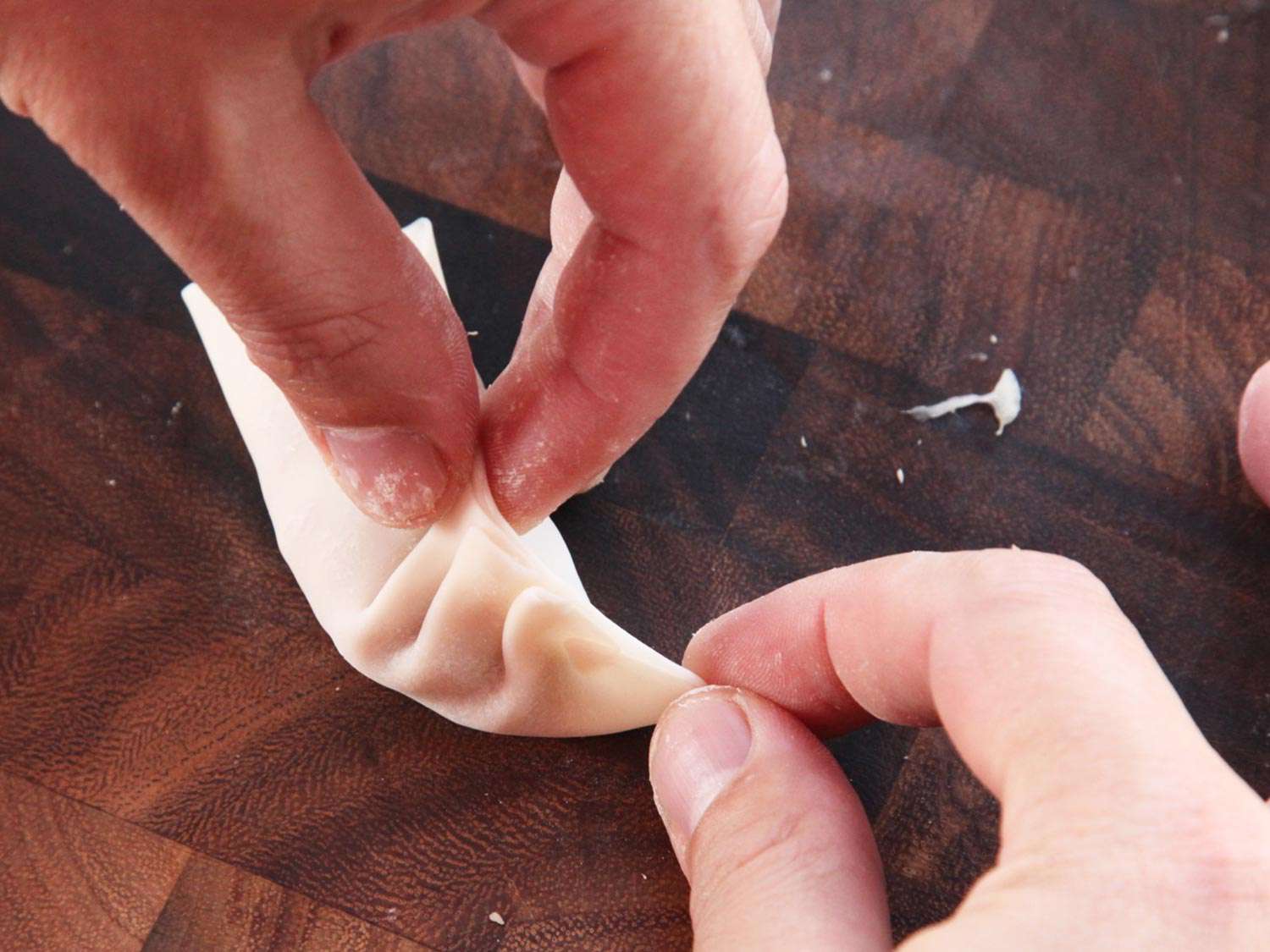 Folding pleats in a dumpling wrapper to form gyoza. 