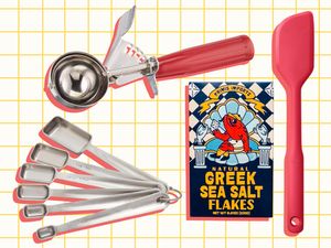 A set of kitchen tools including stainless steel measuring spoons an ice cream scoop a spatula and a box of Greek sea salt flakes