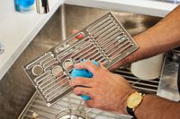 A person cleaning the tray from the Breville Barista Express Impress with a blue sponge