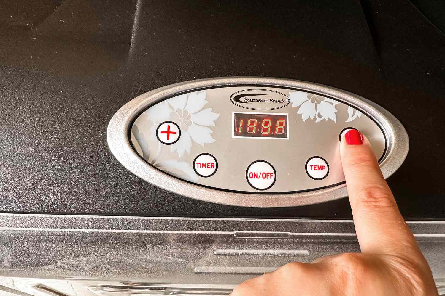 A person setting the temperature on the display of the Samson Silent food dehydrator
