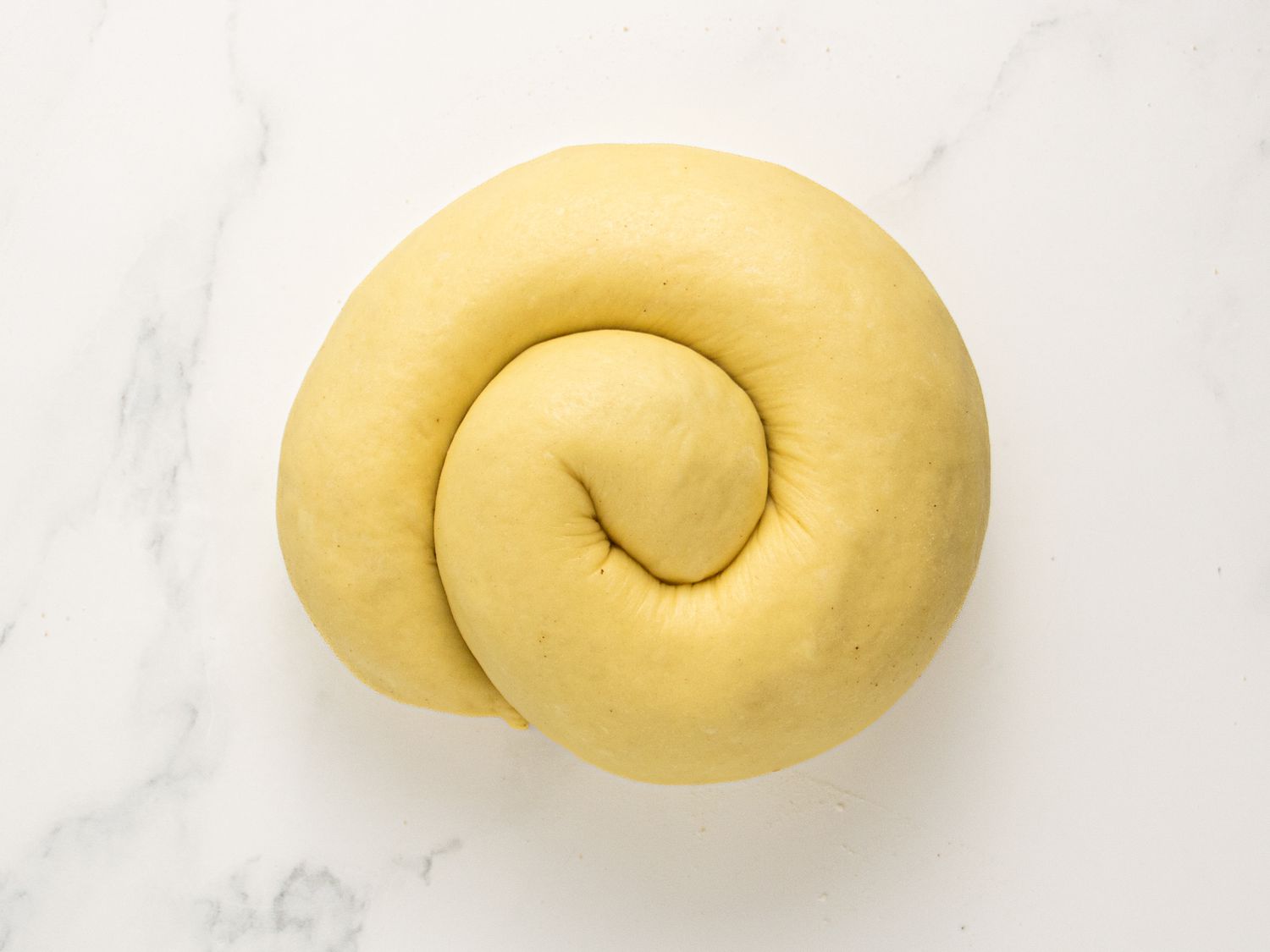 dough coiled together on a white marble surface