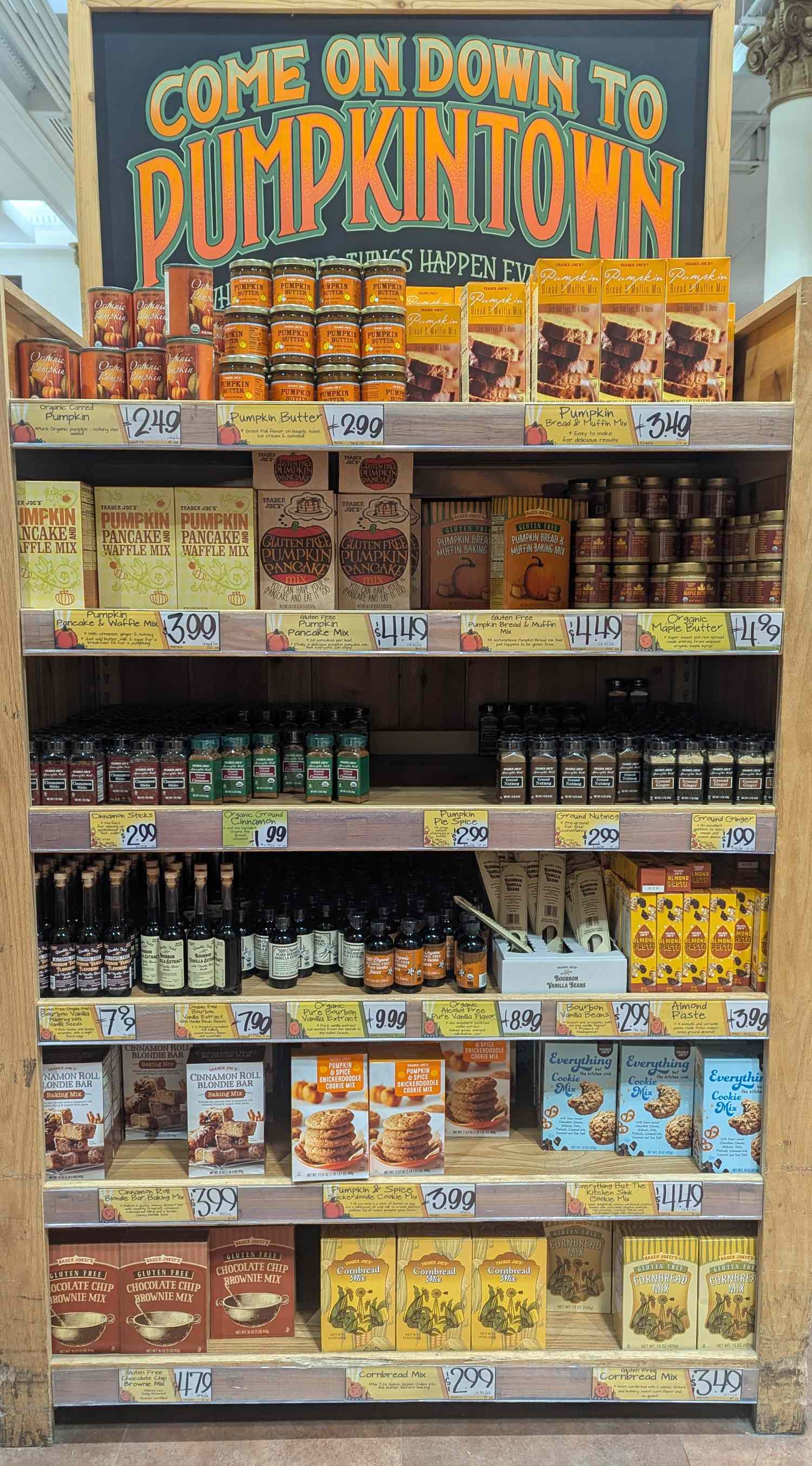 Retail display of assorted pumpkinthemed products at Trader Joes featuring a Pumpkintown header above the shelves