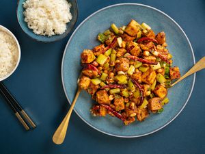 a blue plate full of kung pao tofu against a blue background
