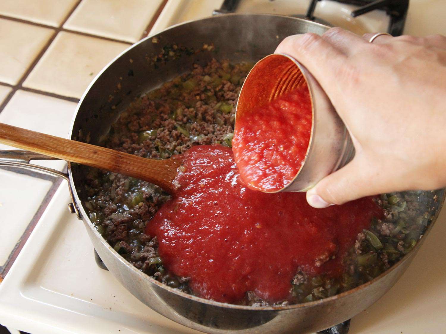 A can of puréed tomatoes is added to the pan. 