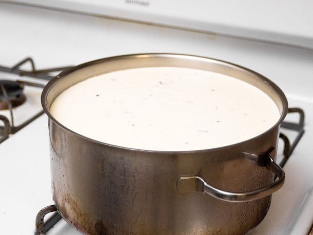 A metal pot filled with ice cream custard on a stove.