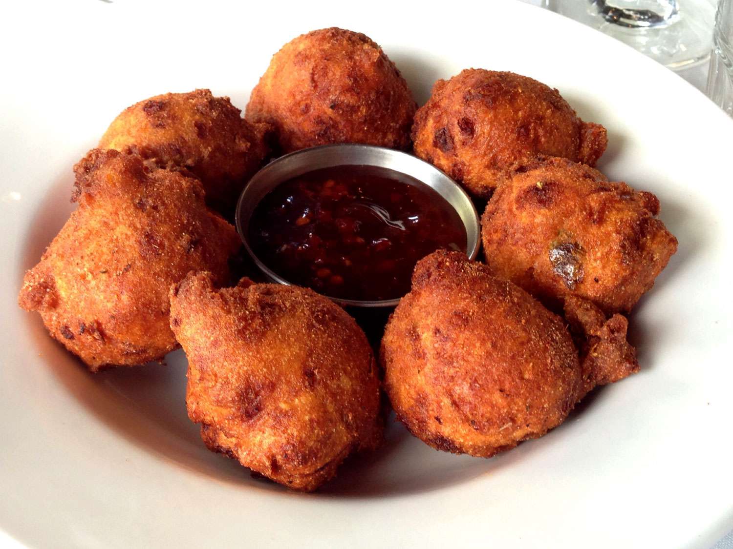 Hushpuppies in a bowl with a sauce in the center.