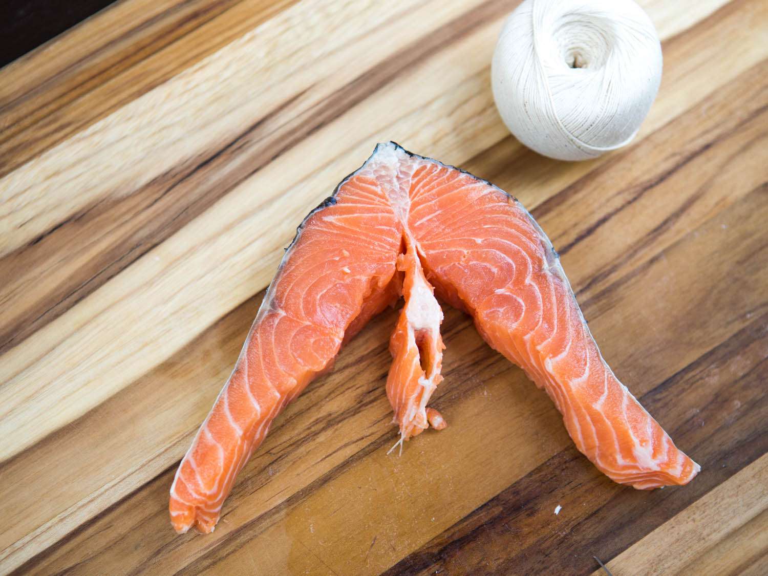 The center spine bone in a salmon steak is almost cut free.