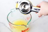 Pouring lemon juice from the KitchenAid citrus juicer into a measuring cup.