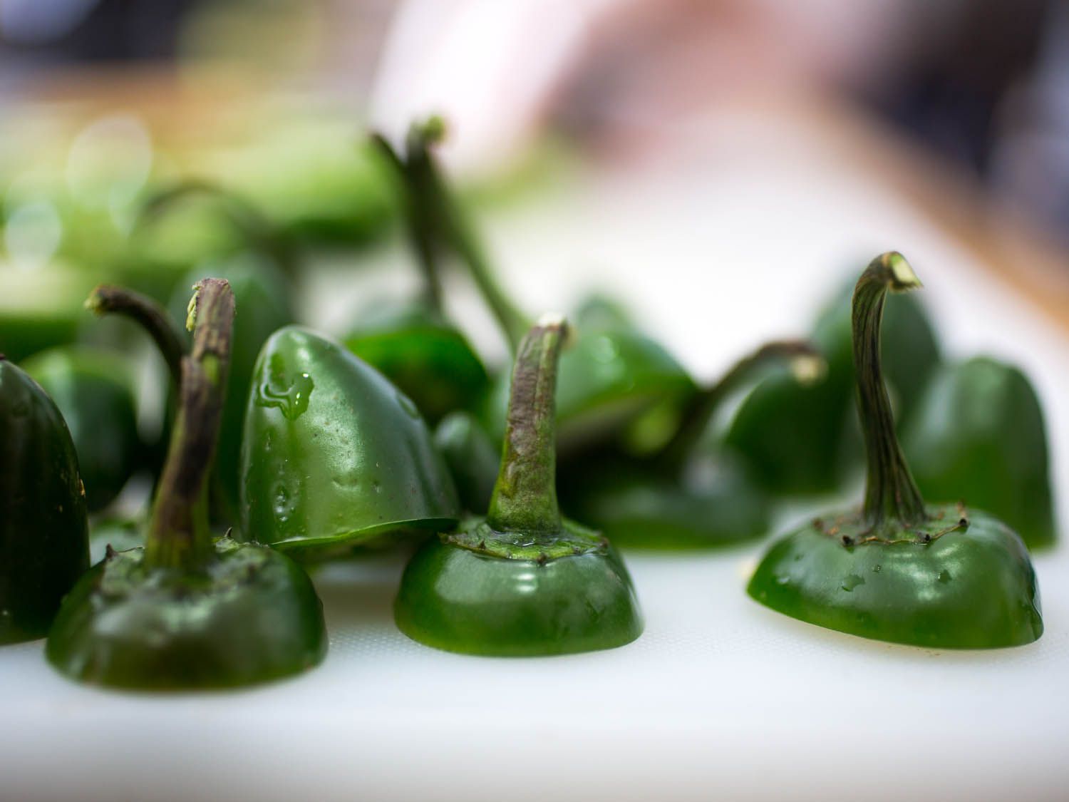 Close-up of the sliced and discarded ends of jalapeños. The stems of several are sticking straight up.
