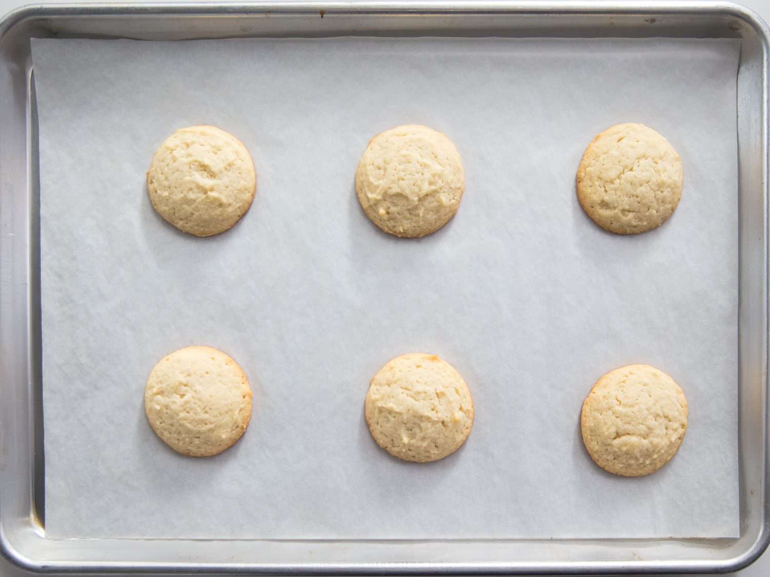Overhead shot of unfrosted Lofthouse-style cookies baked on a parchment-lined baking sheet.
