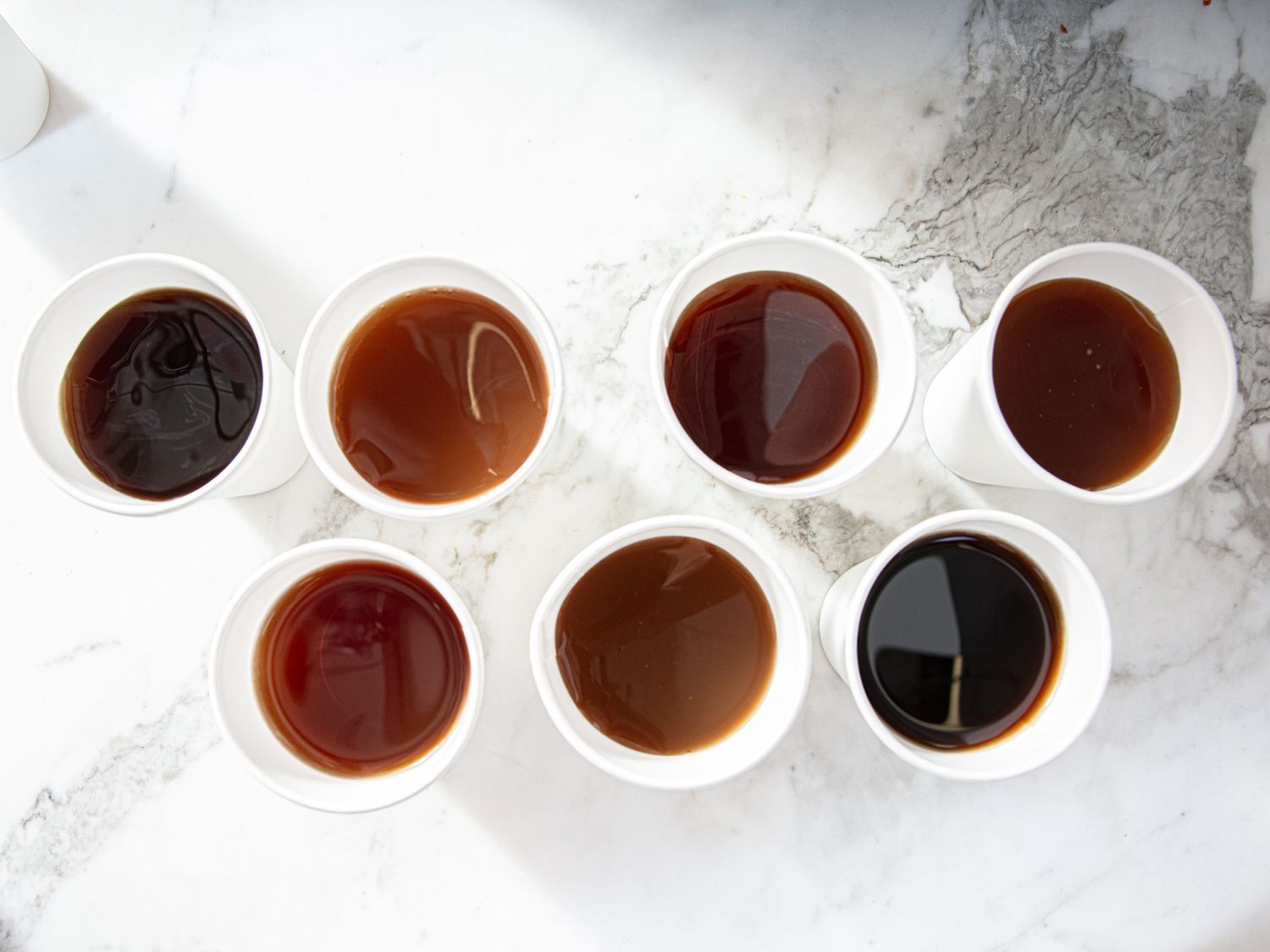 A selection of cups containing different iced tea samples arranged on a surface