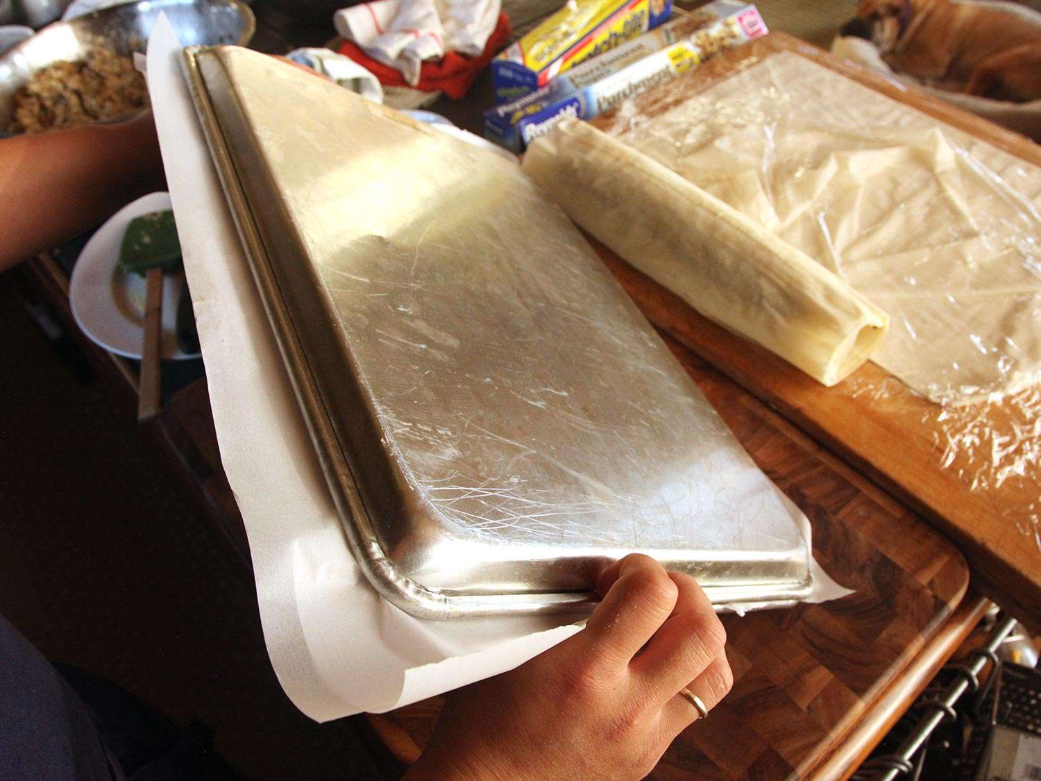Flipping baking sheets to invert bean-cashew puree covered phyllo sheets.