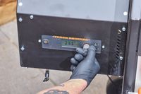 A person turns a dial on the Yoder Smokers YS640S Pellet Grill