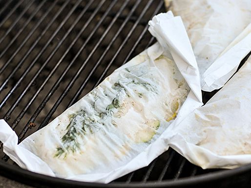 3 parchment pouches with fish sitting on grill racks.