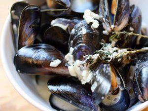 A close-up of mussels just cooked in their shells, with Roquefort cheese and sprigs of fresh thyme