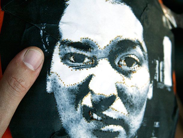 A photograph of a face taped on a pumpkin, with holes poked through to delineate areas of light and dark in the photo