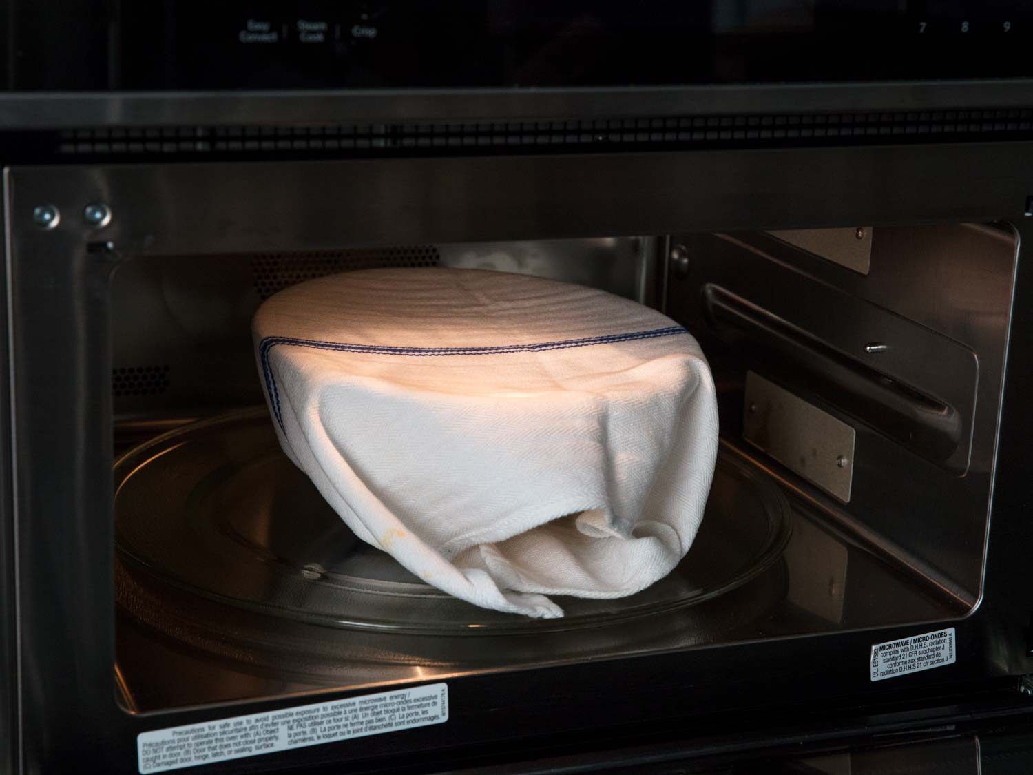 A covered bowl of rice cooking in microwave.