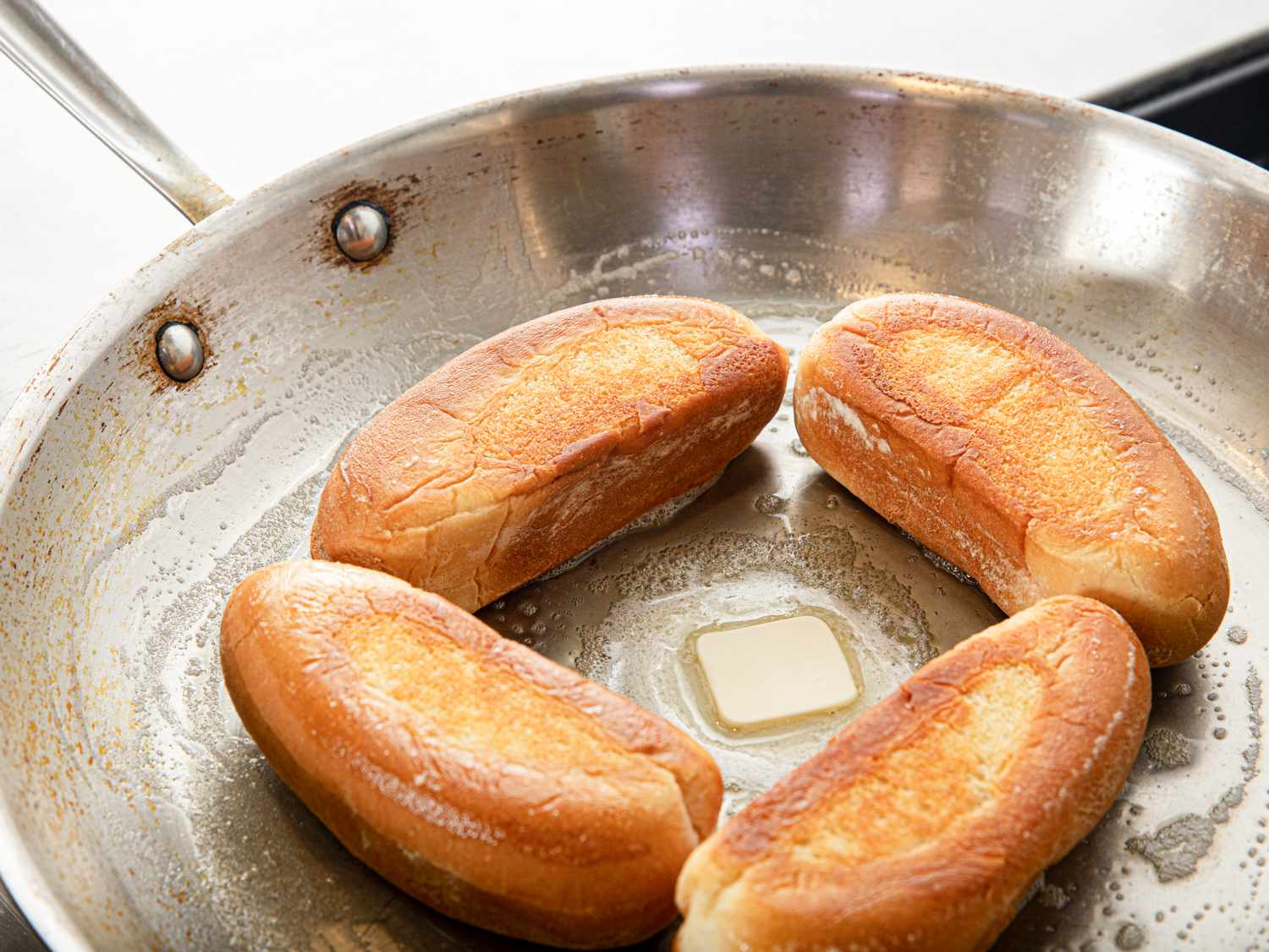 4 buns toasting in butter in a pan